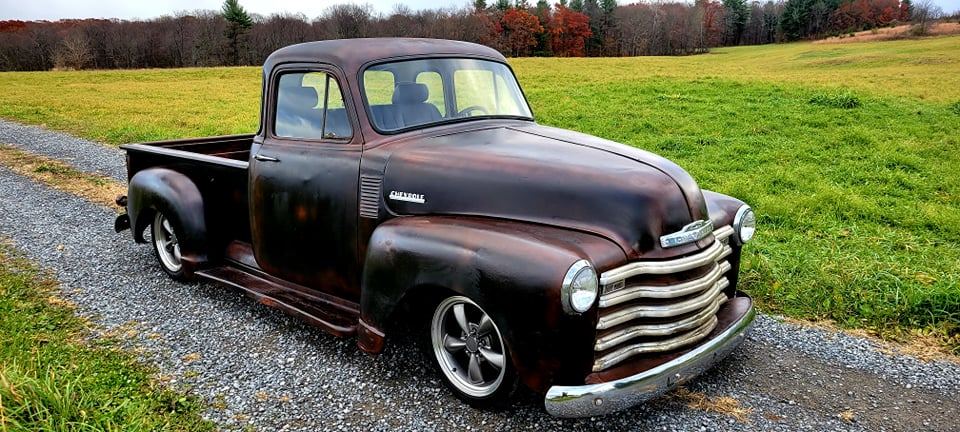 Dark patina Chevrolet pickup on a gravel road